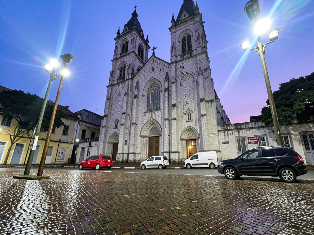 Vista da Catedral da Sé a partir da praça, com detalhes arquitetônicos e movimento de pessoas.